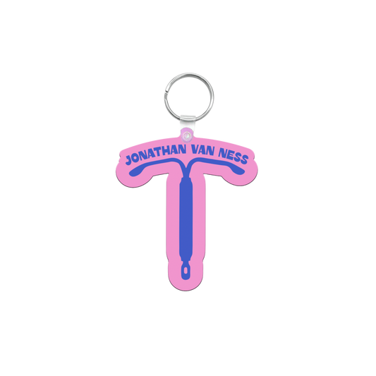 A pink and blue IUD shaped keychain featuring the text 'JONATHAN VAN NESS' in blue, with a silver metal key ring at the top