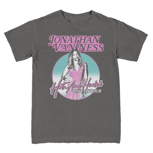 A charcoal gray t-shirt featuring a graphic print of Jonathan Van Ness in pink and light blue, with the text 'JONATHAN VAN NESS' and 'Hot And Healed LIVE ON TOUR'.