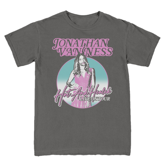 A charcoal gray t-shirt featuring a graphic print of Jonathan Van Ness in pink and light blue, with the text 'JONATHAN VAN NESS' and 'Hot And Healed LIVE ON TOUR'.